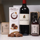 A bottle of red wine labeled "Chevalier de Montlort" stands in the center, flanked by a box of Lily O'Brien's "Sticky Toffee" chocolates and a bottle of hand lotion. The products are arranged neatly against a soft background. A bottle of red wine labeled "Chevalier de Montlort" stands in the center, flanked by a box of Lily O'Brien's "Sticky Toffee" chocolates and a bottle of hand lotion. The products are arranged neatly against a soft background.